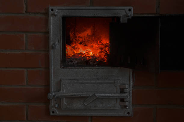 istock Russian old retro fireplace with firewood in the living room. Orange, hot flames in the dark atmosphere. House manual heating concept in winter time. 893473124