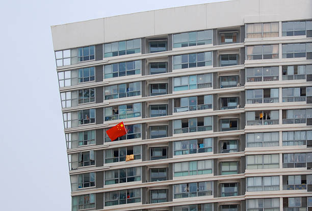 Single Chinese flag waves patriotically from modern tower block stock photo