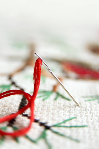 istock Cross-stitch embroidery and needle with red thread. Embroidery macro close up. View from above. Free copy space. 893481808