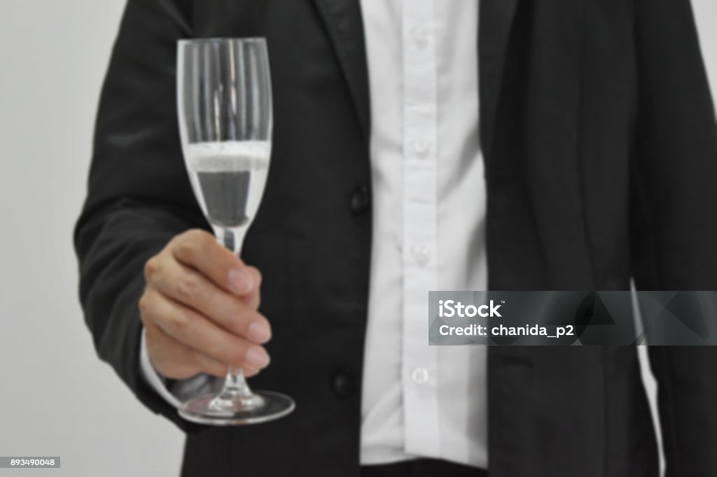 The background blur, a businessman holding a wine glass standing posture. The background blur, a businessman holding a wine glass standing posture , Empty with copy space for text. Human Hand Stock Photo