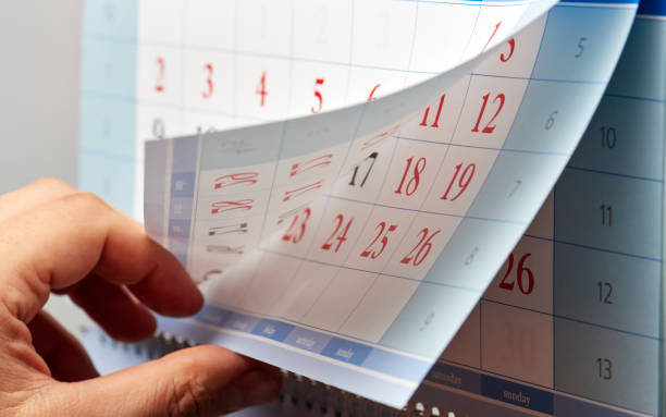 istock Hand flipping through sheets of wall calendar 893496802