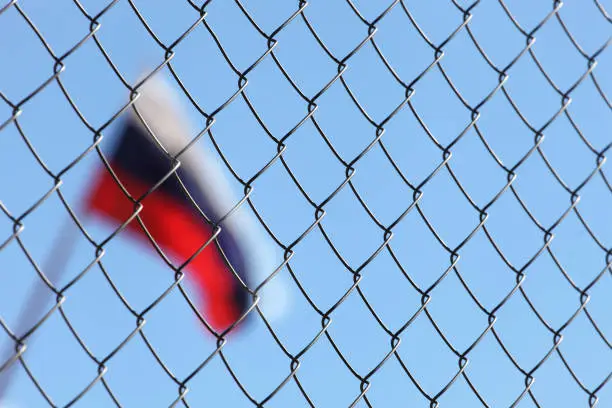 a fence of metal mesh behind which the Russian flag
