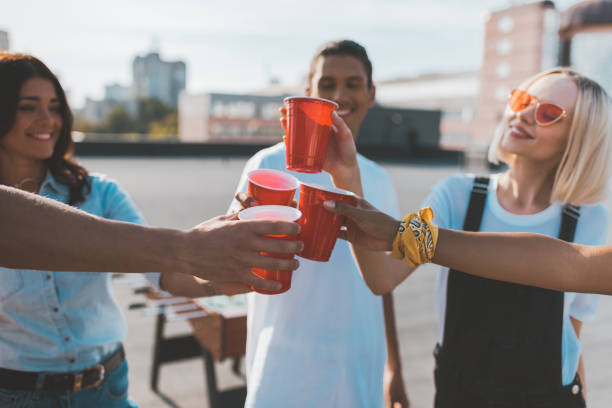 group of friends clinking glasses group of friends clinking glasses on alcohol on roof party red party cup stock pictures, royalty-free photos & images