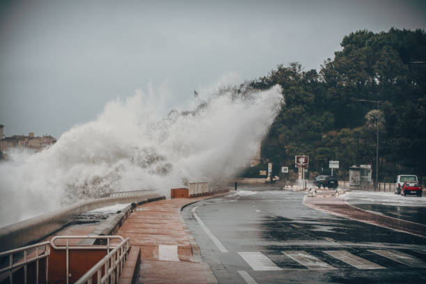 eng stormachtige achtergrond met grote zee wave splash tegen city road - tyfoon fotos stockfoto's en -beelden