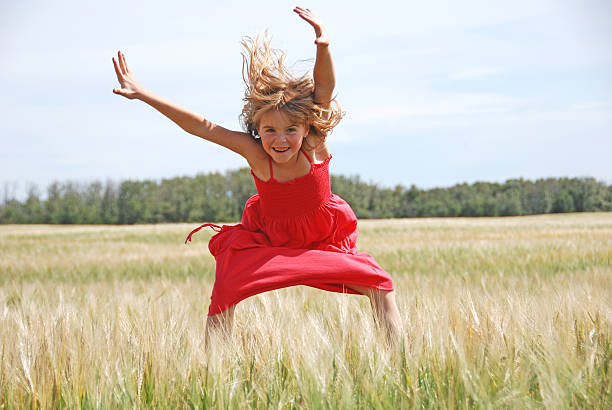 A young girl with orange hair jumps happily and contentedly during a walk in a natural rural area