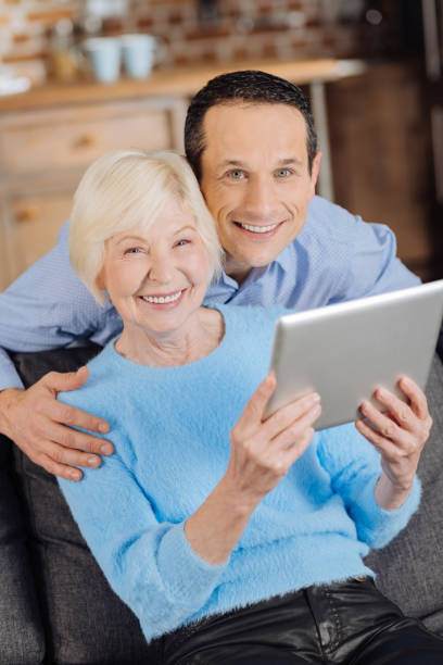 istock Cheerful senior mother and son posing while watching video 893512376