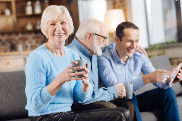 istock Cheerful senior woman posing with coffee cup on couch 893517500