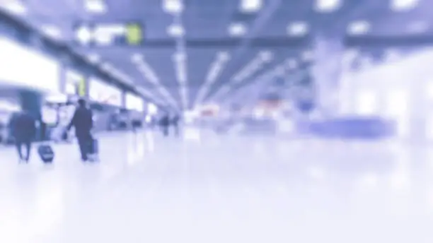 abstract blur image of  passenger walking at baggage claim area in airport with defocused, for background usage . (Light blue tone)