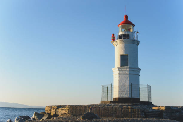 Lighthouse on the seacoast at sunset light. Nature background. Free copy space.