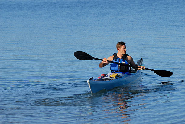 Athletic man backs into bay in kayak stock photo