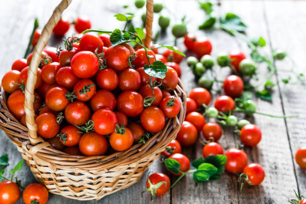 korb mit tomaten aus holz hintergrund, frische kirschtomaten fordert produzieren am lokalen markt - cherry tomato fotos stock-fotos und bilder