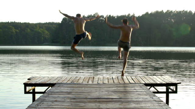 Friends jumping into lake. Summer activity