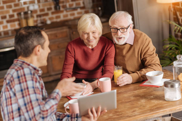 istock Caring son demonstrating video to his senior parents in kitchen 893526274