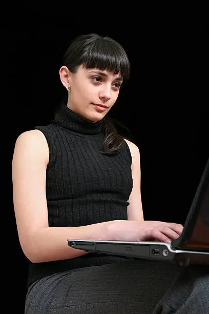Beautiful young girl is writing at the laptop