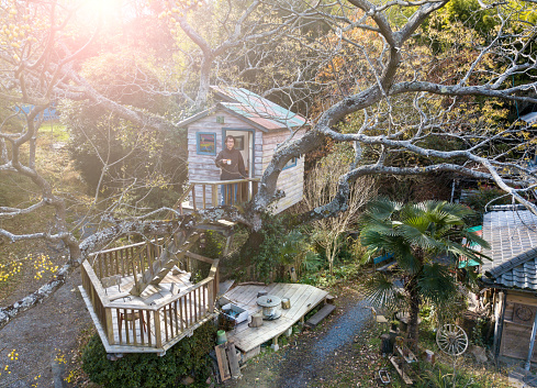 Aerial shot of a man in a tree house drinking coffee and enjoying the view