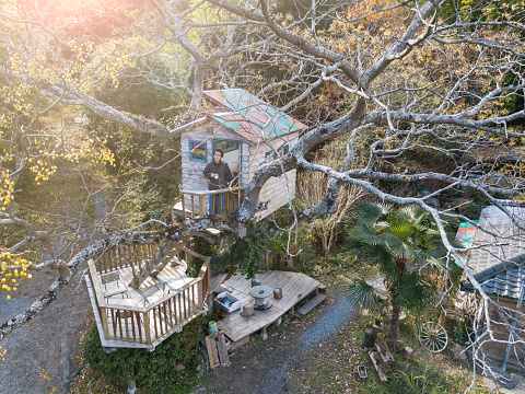 Aerial shot of a man in a tree house drinking coffee and enjoying the view