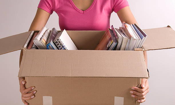 Woman holding open cardboard box of books stock photo