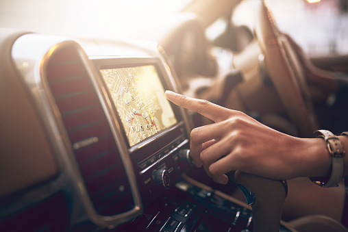 Shot of an unidentifiable businesswoman using her car's built-in GPS while driving