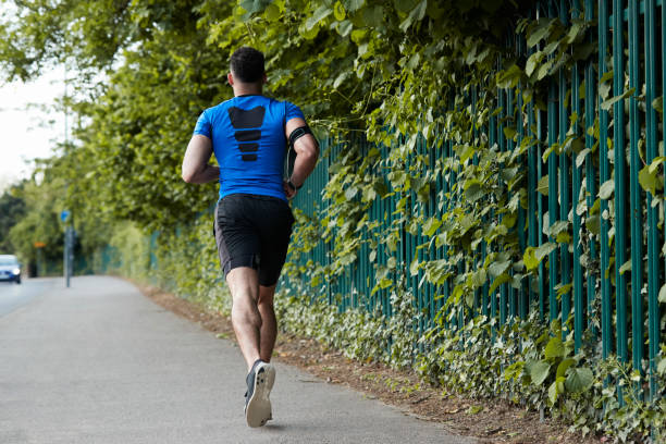 istock Back view of young male athlete running in the street 893543708