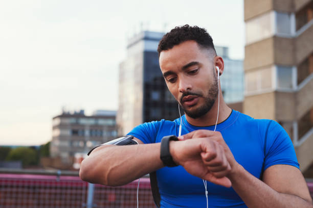 Male runner uses app on smartwatch in urban street, close up Male runner uses app on smartwatch in urban street, close up britain british audio stock pictures, royalty-free photos & images