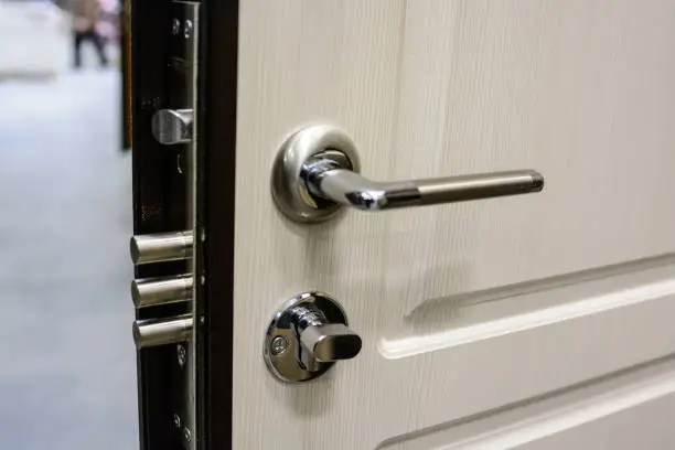 Close-up of metal bronze door handle and lock on white wooden door