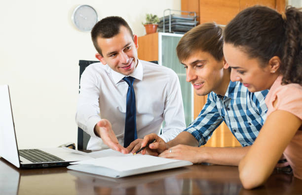 istock Agent with laptop and young couple 893560292