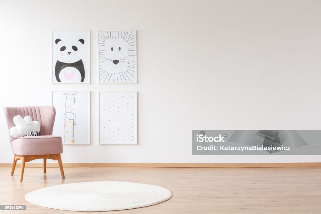 Pink armchair in baby's room Pink armchair with pillow and white round carpet in baby's room with posters on wall with copy space Child Stock Photo