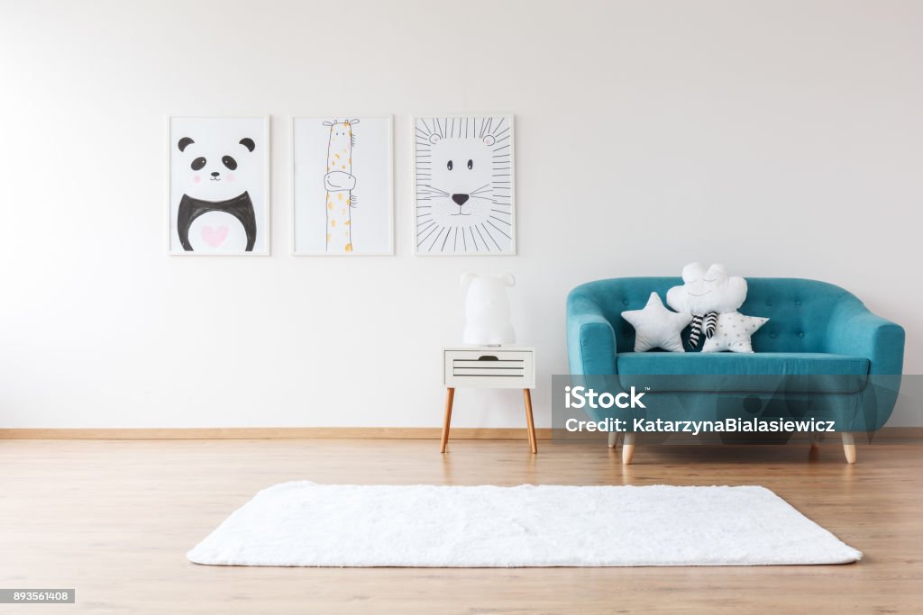 Aquamarine sofa in kid's room White cushions on aquamarine sofa next to cabinet and carpet in kid's room with posters Child Stock Photo