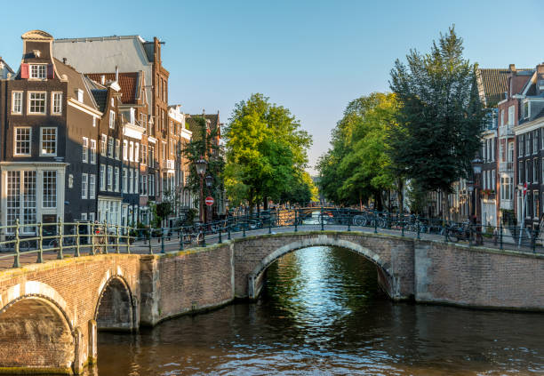 Amsterdam City Scene. Visible are many typical dutch houses in raw and their reflection in the canal. Old 17th and 18th century brick houses along a canal in center of Amsterdam. This image is GPS tagged