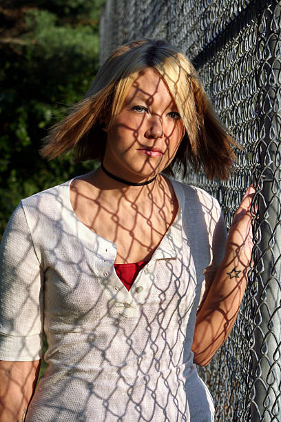 Joven mujer rubia está cubierto por valla sombra - foto de stock