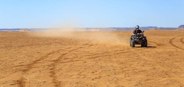 vista panorâmica de homem bicicleta atv quad na areia no deserto em um dia ensolarado - off road vehicle quadbike motocross desert - fotografias e filmes do acervo