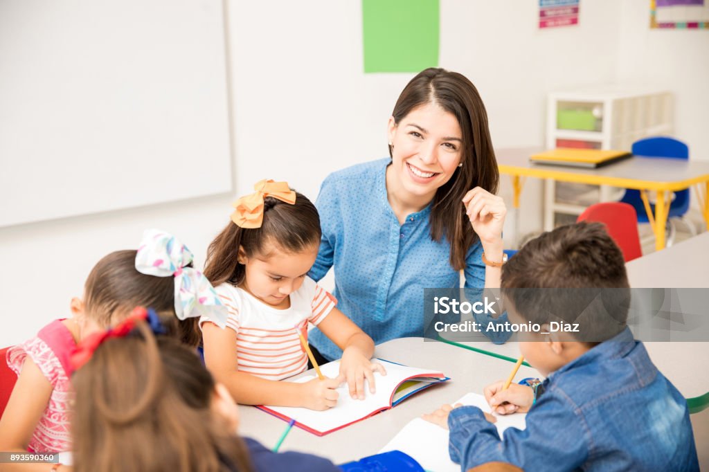 Beautiful preschool teacher during class Portrait of a gorgeous Hispanic preschool teacher teaching her students in a classroom Teacher Stock Photo