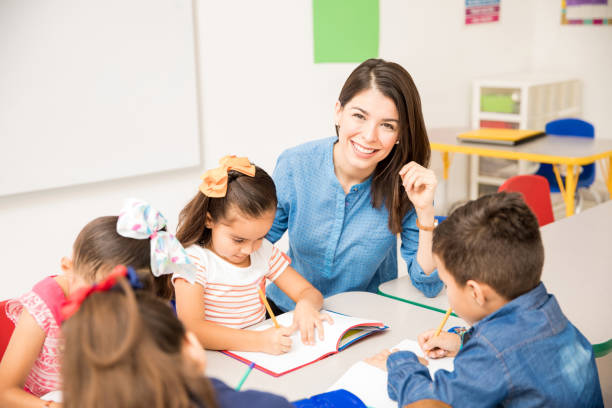 Beautiful preschool teacher during class Portrait of a gorgeous Hispanic preschool teacher teaching her students in a classroom child care photos stock pictures, royalty-free photos & images