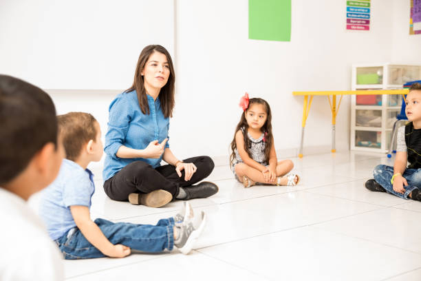 istock Preschool teacher sitting in the floor 893590404