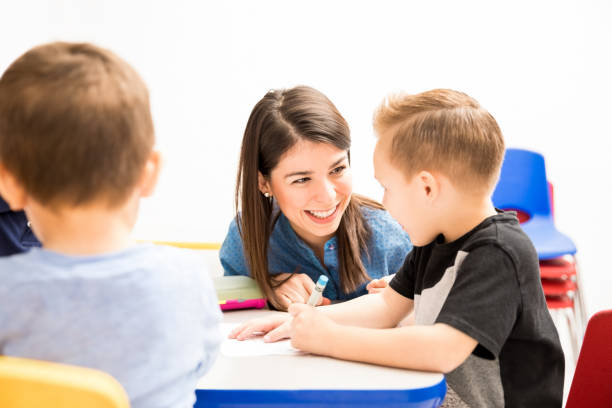 istock Happy teacher helping one of her students 893601804