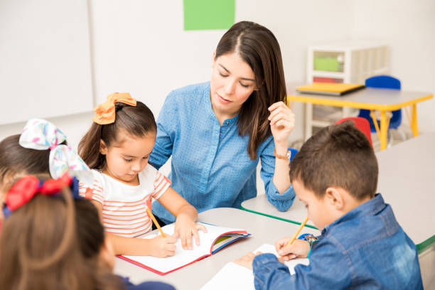 istock Preschool teacher helping her pupils 893603430