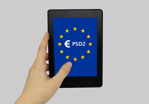 Hand holding tablet device with screen displaying PSD2 on EU flag
