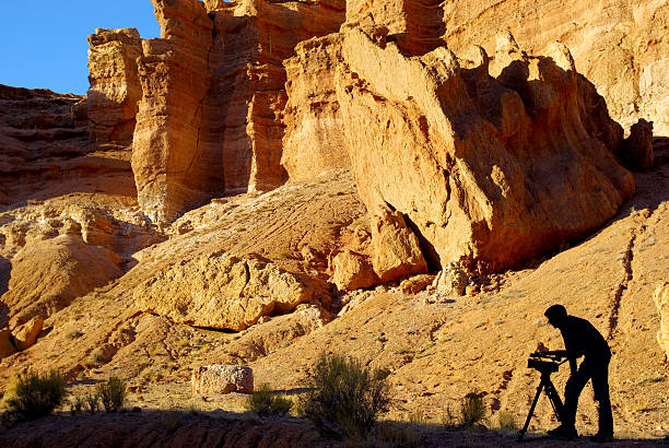 silhouette d'un homme avec caméra vidéo de canyon - arid climate travel destinations canyon dawn photos et images de collection