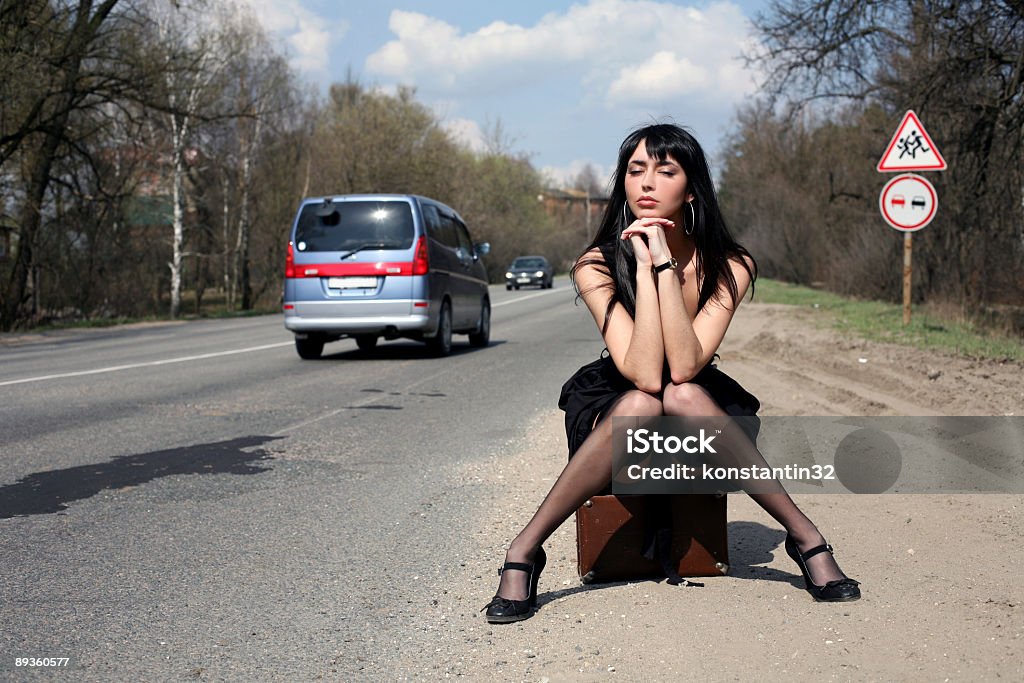 girl in the road sit atop vintage suitcase - Royaltyfri Sensualitet Bildbanksbilder