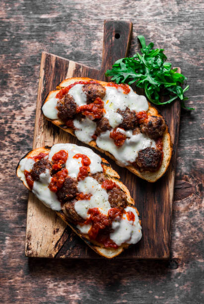 polpette, salsa di pomodoro, mozzarella e panini caldi di rucola su un tagliere rustico su un tavolo di legno, vista dall'alto. delizioso spuntino, colazione, antipasto - mozzarella tomato sandwich picnic foto e immagini stock