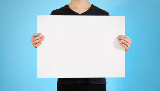 istock Man showing blank white big A2 paper. Leaflet presentation. Pamphlet hold hands. Man show clear offset paper. Sheet template. Booklet design sheet display read first person. 893610462