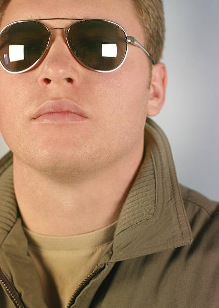 Green-tinted sunglasses are showcased on a flat surface, reflecting light. The sleek design and modern style suggest they are perfect for outdoor activities on a sunny day.