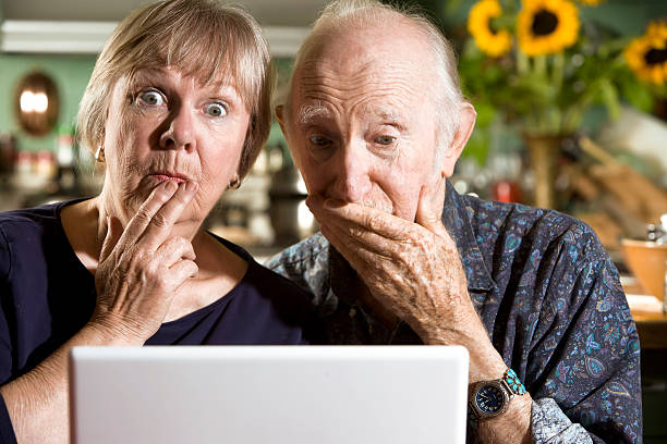 perplexe senior couple avec un ordinateur portable - women computer couple surprise photos et images de collection