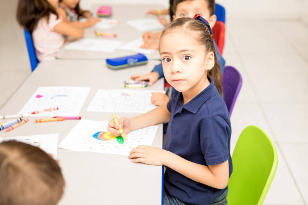 istock Cute Latin girl coloring in a classroom 893678436
