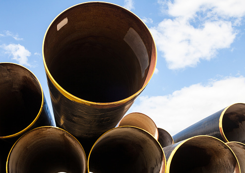 Stack of new metal pipes with yellow-painted edges. Industrial material.