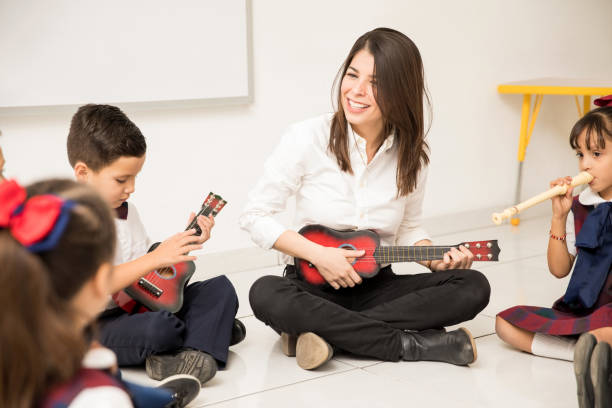 istock Preschool teacher playing the guitar in class 893715620