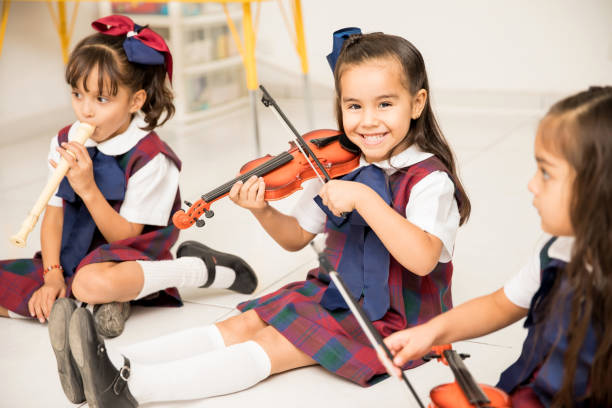 счастливая девочка играет на скрипке в дошкольном учреждении - latin american and hispanic ethnicity child violin music стоковые фото и изображения