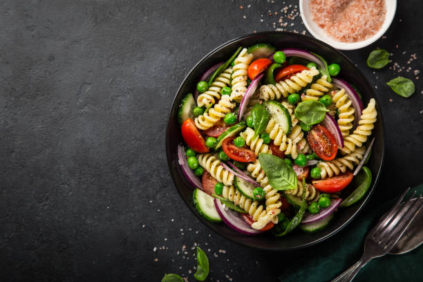 istock pasta salad with tomato, cucumber, spinach and grean peas 893756624