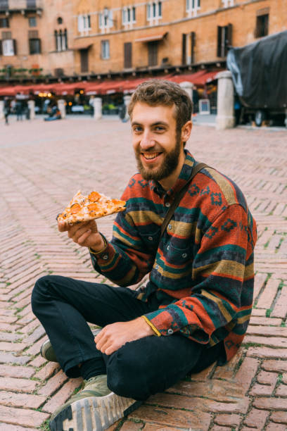 istock Man eating pizza on Piazza del Campo in Siena 893763940