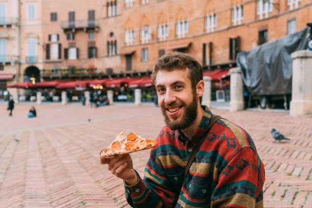 istock Man eating pizza on Piazza del Campo in Siena 893763946